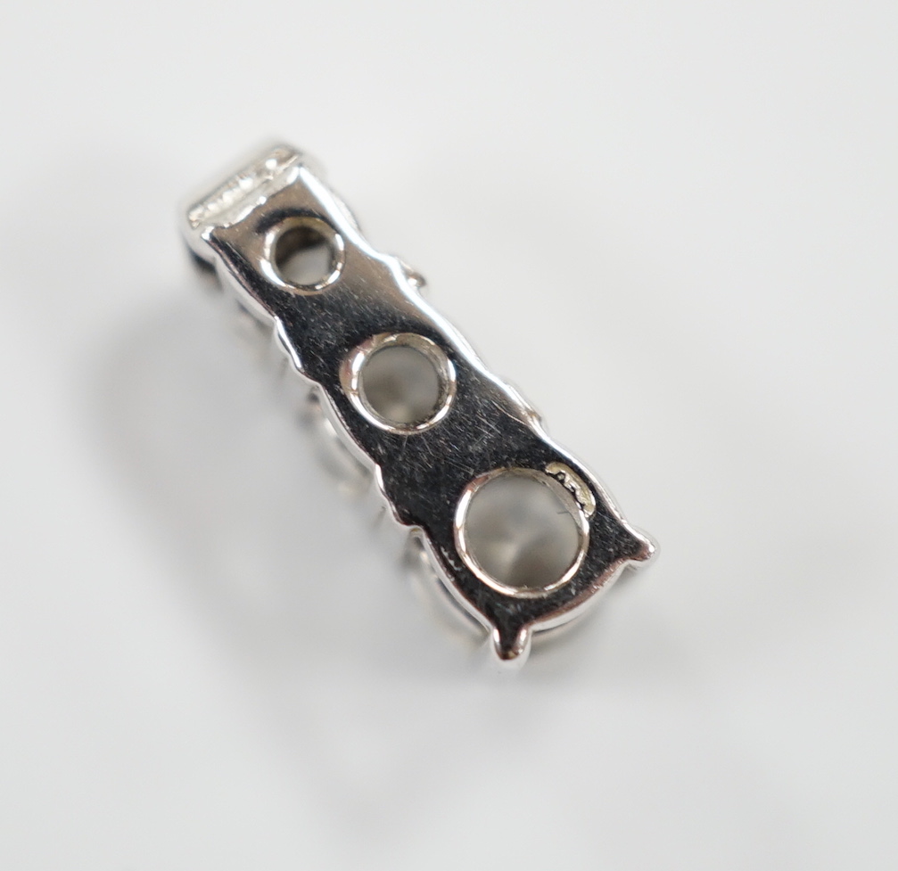 A modern white metal and graduated three stone diamond set pendant, 10mm, gross weight 1 gram.